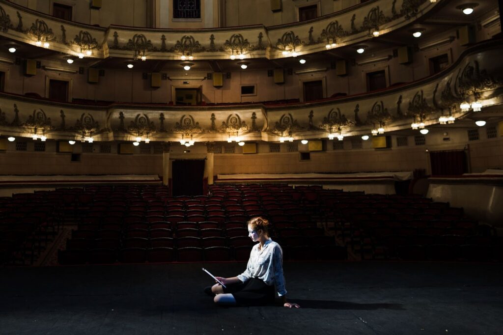 Mime reading manuscript on stage in empty auditorium